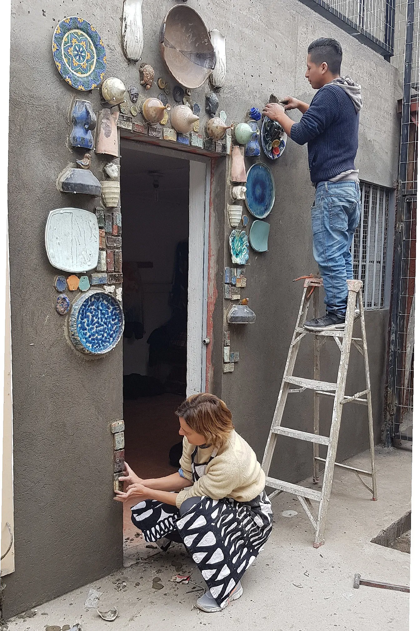 Sofía Donovan instalando cerámicas en la fachada del taller